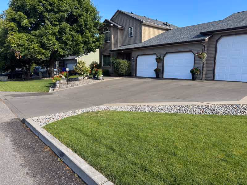 Freshly resurfaced concrete driveway beside a green lawn in Spokane Valley