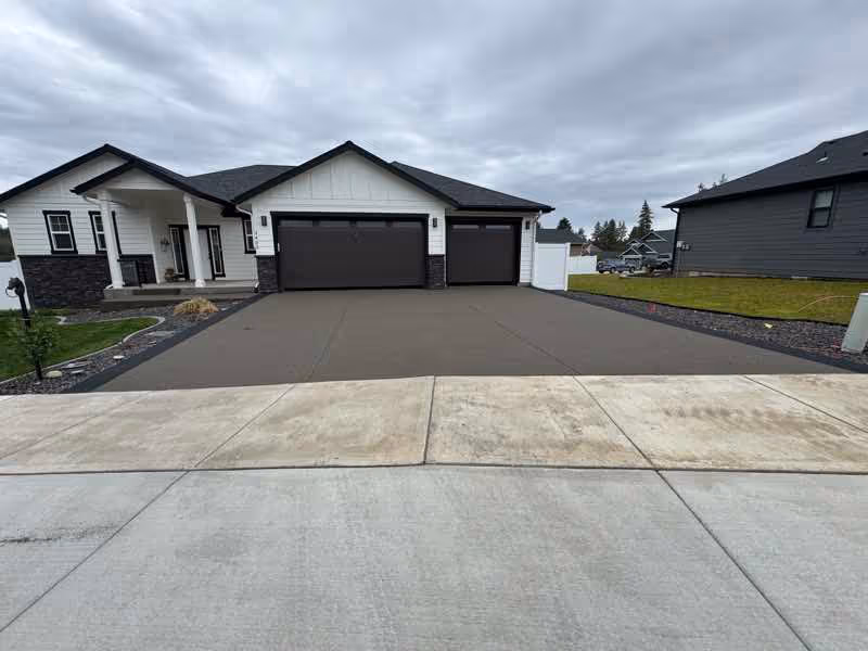 Resurfaced gray concrete driveway in front of a modern Spokane Valley home